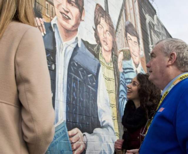 Photo of people on a cab tour, looking at a wall monument in Belfast.