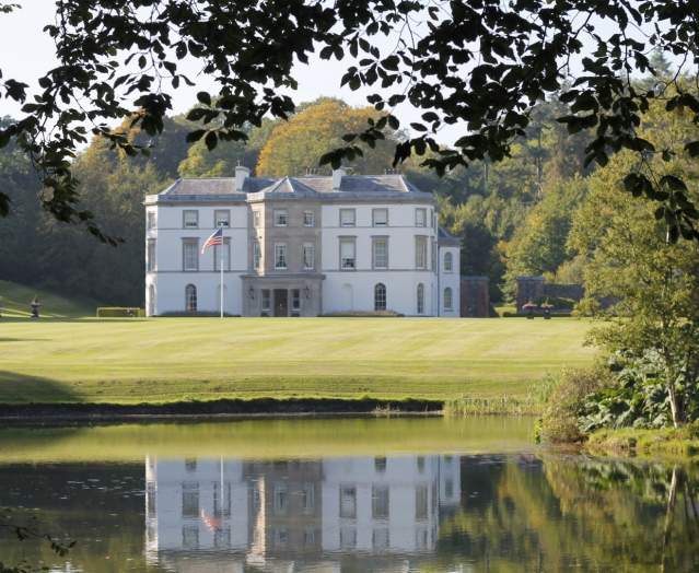 Exterior shot of Montalto House with an American flag on the grass and a lake visible at the front of the shot.