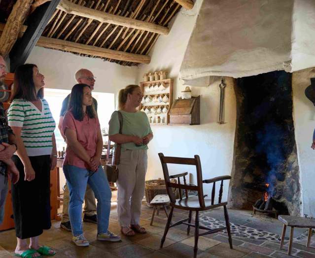A group of visitors listening to the tour guide inside Andrew Jackson Cottage standing by the fire