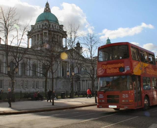 City Sightseeing Belfast bus going past landmark buildings in Belfast