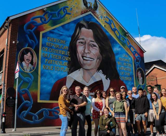 Visitors standing in front of mural on a building wall