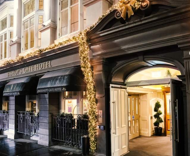 Exterior of Bishop's Gate Hotel decorated with festive lights, showcasing the elegant entrance and stylish architecture.