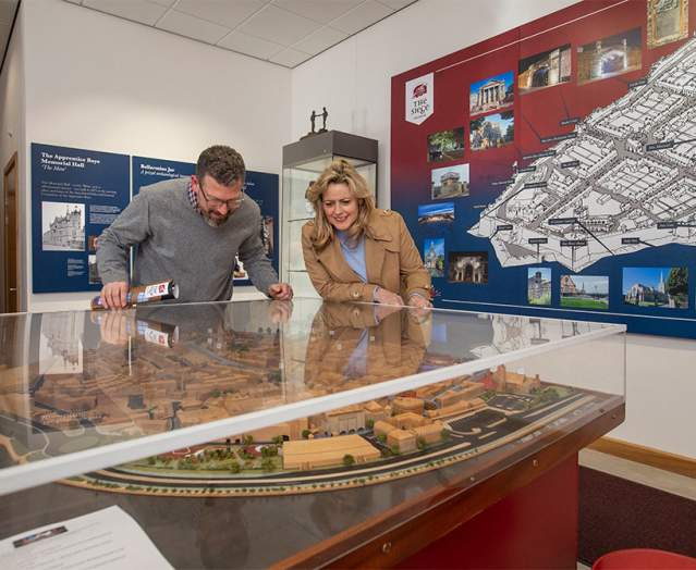 Two visitors enjoying the exhibitions at the Siege Museum in Derry-Londonderry, looking over a glass case with a model village inside