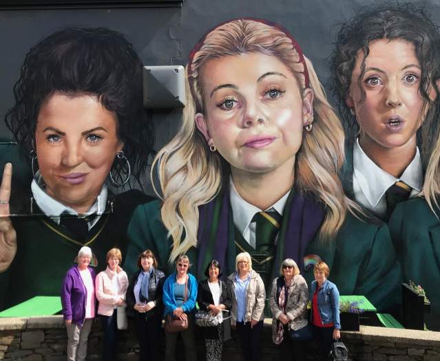 Visitors standing in front of the Derry Girls mural