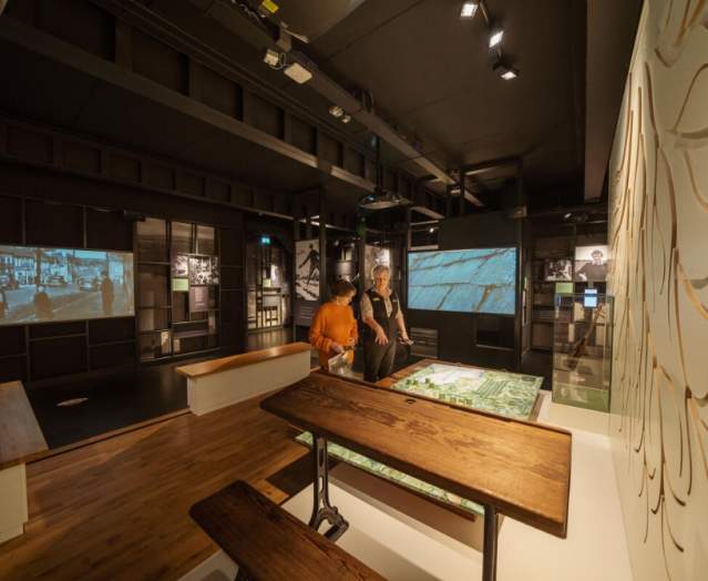 Group of visitors being shown round an exhibition at Seamus Heaney HomePlace