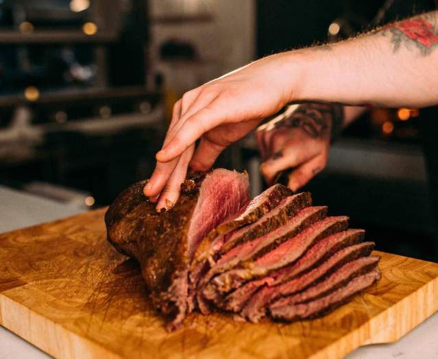 A chef slicing a large piece of beef for Sunday Lunch