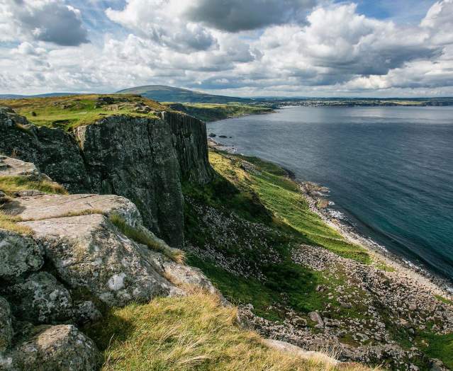 Cliff view from Fair head over looking blue still water and blue skies