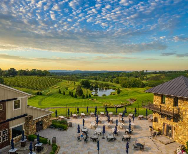 Aerial view of Stone Tower Winery's outdoor patio and rolling vineyard at sunset in Leesburg, Virginia.
