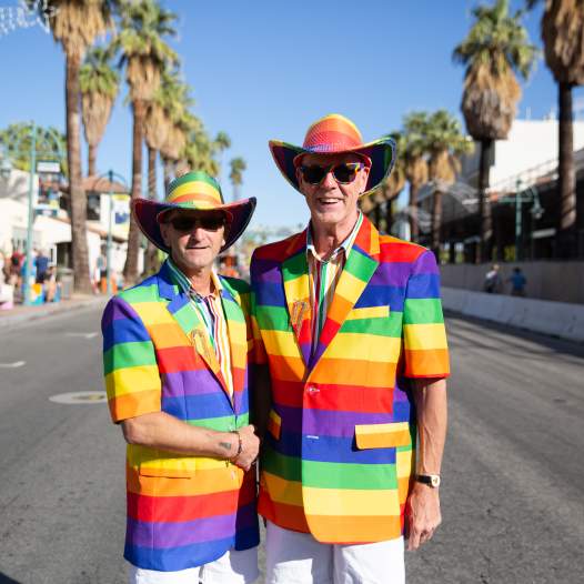 Two gay men in rainbow colored outfits celebrating Palm Springs Pride