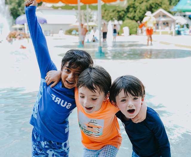 Three young boys smiling at the waterpark.