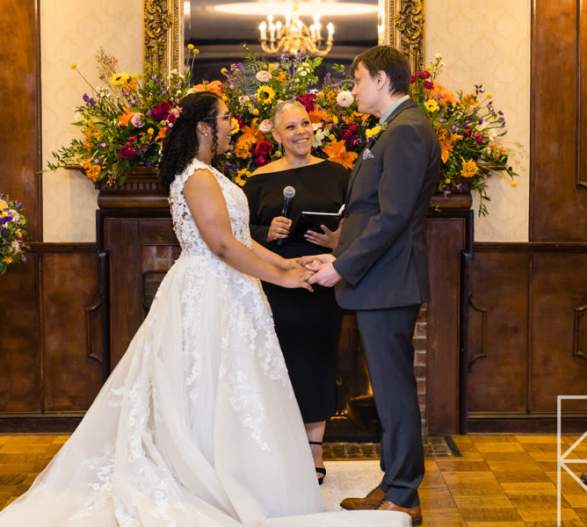 Wedding officiant performing a ceremony with bride and groom holding hands