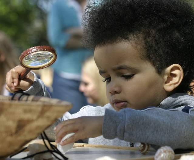 Child with a magnifying glass at the Roger Williams Park Zoo