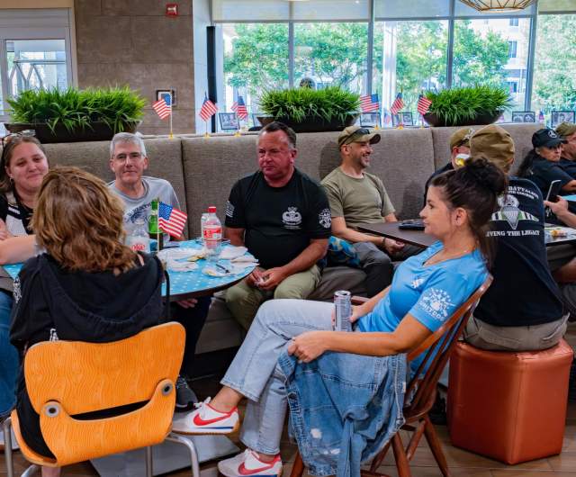 Group of adults seated together at tables, talking and reconnecting during a casual reunion gathering in Greater Fayetteville.