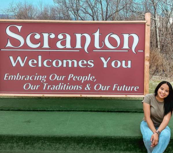 woman sitting in front of Scranton Welcomes You Sign