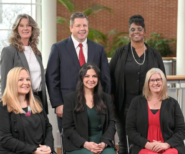 Diverse team of six Akron event planners posed indoors in a bright, modern workspace