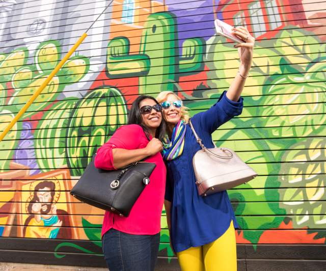 Friends pose for a selfie in front of a mural at SanTan Brewing Co. in Chandler, AZ
