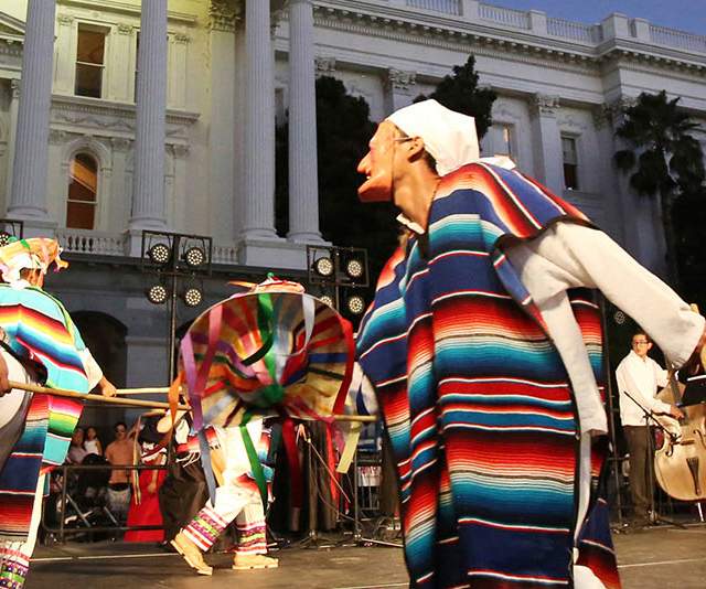 people dressed in sarapes dancing in front of the capital building