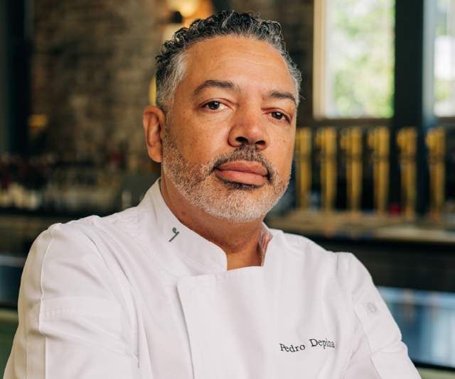 Pedro Depina of the 7th Street Standard stands confidently in a white chef's coat