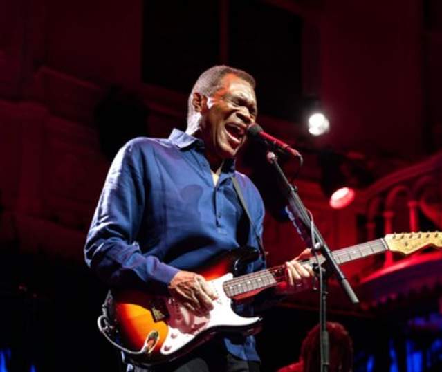 Robert Cray singing passionately with his guitar in hand