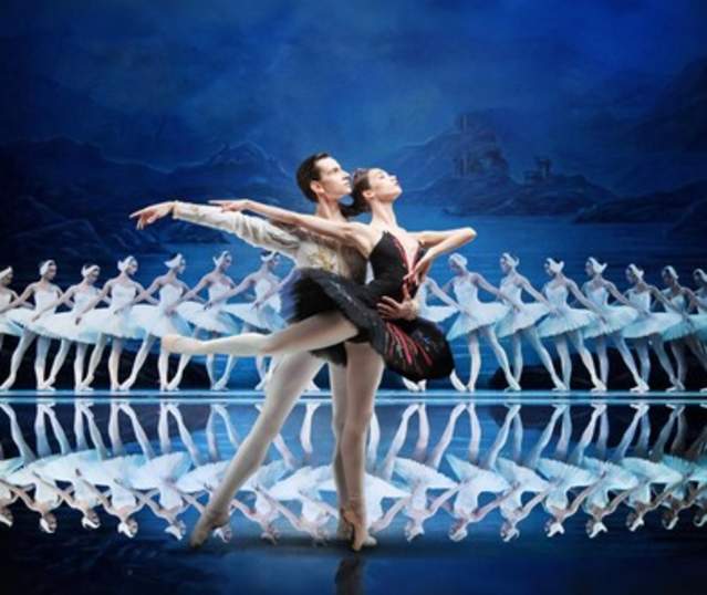 Two ballet dancers mid performance with a line of dancers behind them