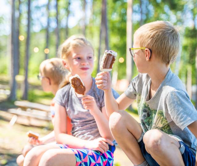 Tre barn sitter og spiser is