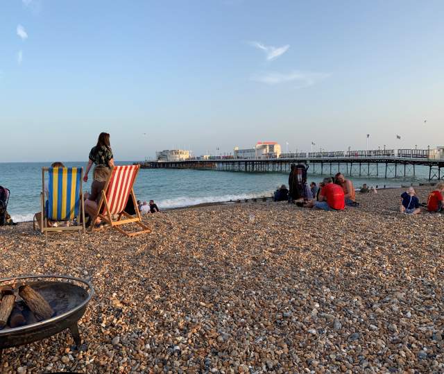 Group of people enjoying a BBQ on the beach at Worthing, with a view of Worthing Pier
