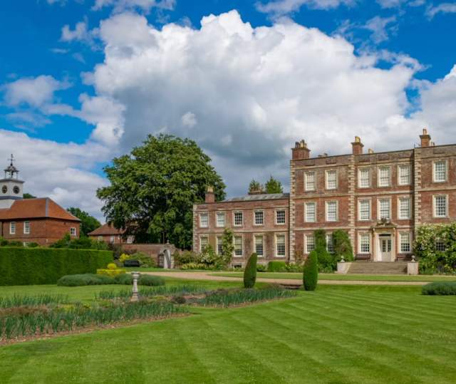 A historic house with grass in foreground and blue skies