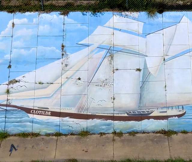 A mural painted on a concrete wall depicts the Clotilda ship