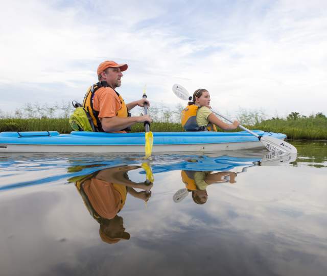 man and young girl kayaking in a blue kayak
