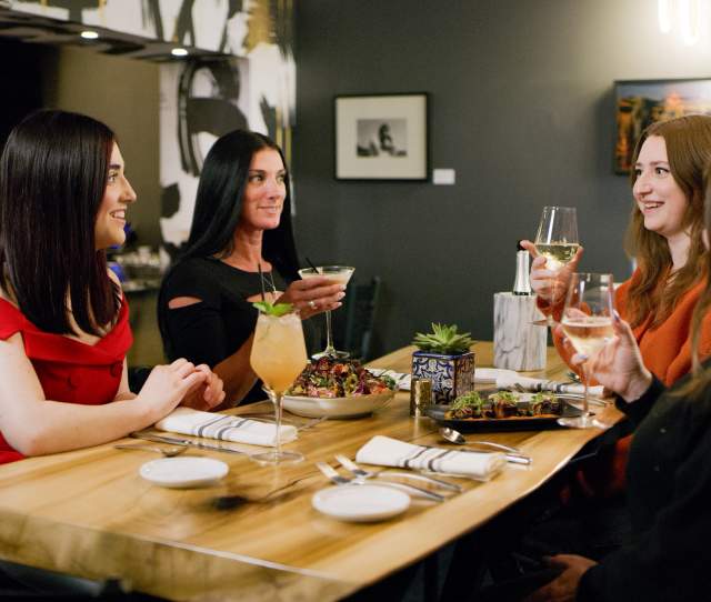 4 women sit at a restaurant table dining on gourmet food