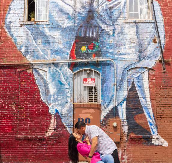 Couple kissing in from of mural