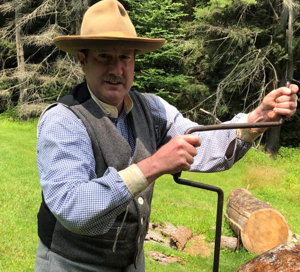 Man with a hat on cranking a tool into the ground