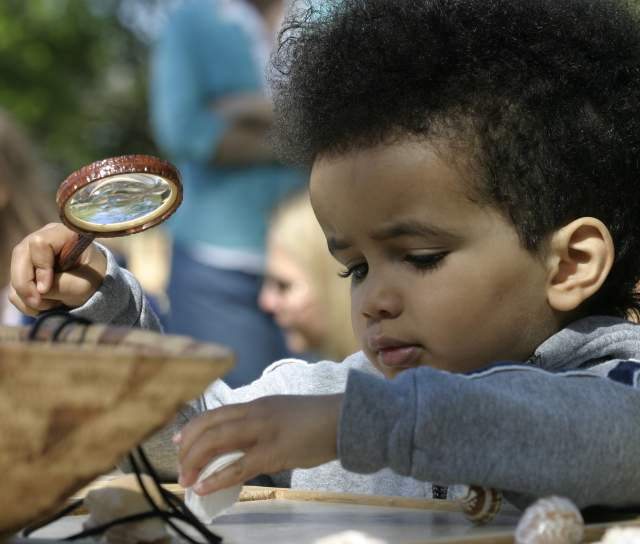 Child with a magnifying glass at the Roger Williams Park Zoo