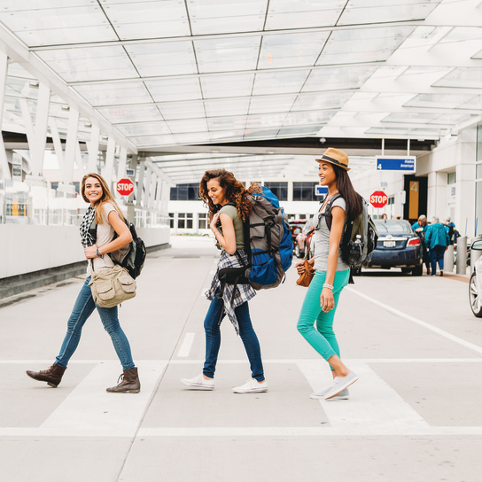 three women smiling after getting baggage and walking out of airport