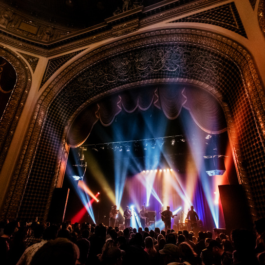 inside view of the Pabst Theater with concert ongoing, bright lights, crowd