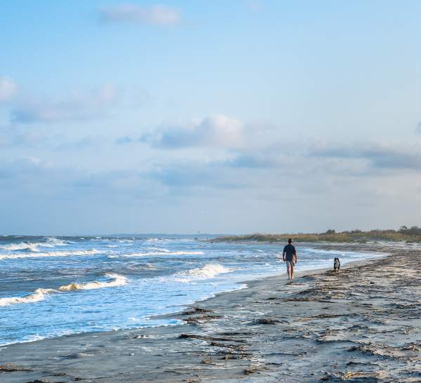 A beachgoer enjoys a walk along the shore of St. Simons Island beach