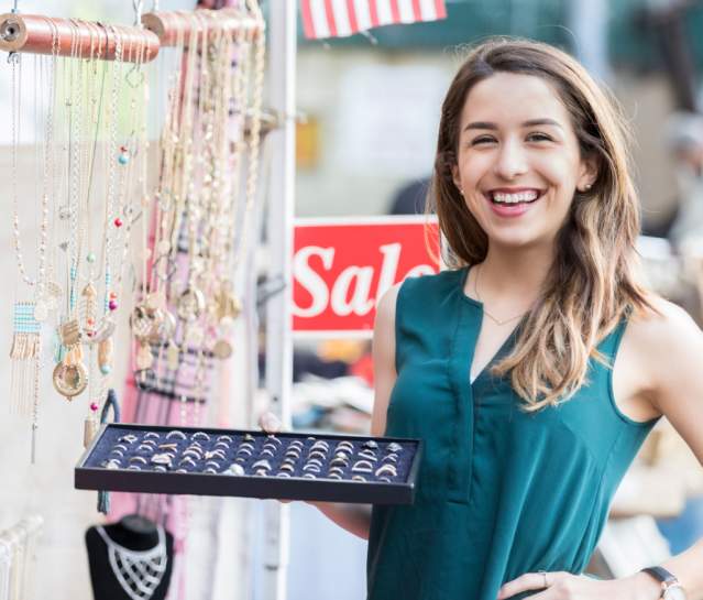Jewelery vendor showing rings and smiling