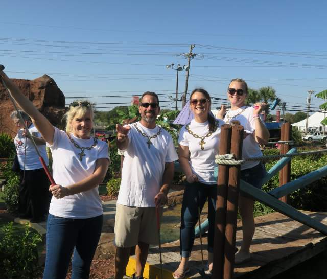 Team of miniature golfers posing on a miniature golf course.