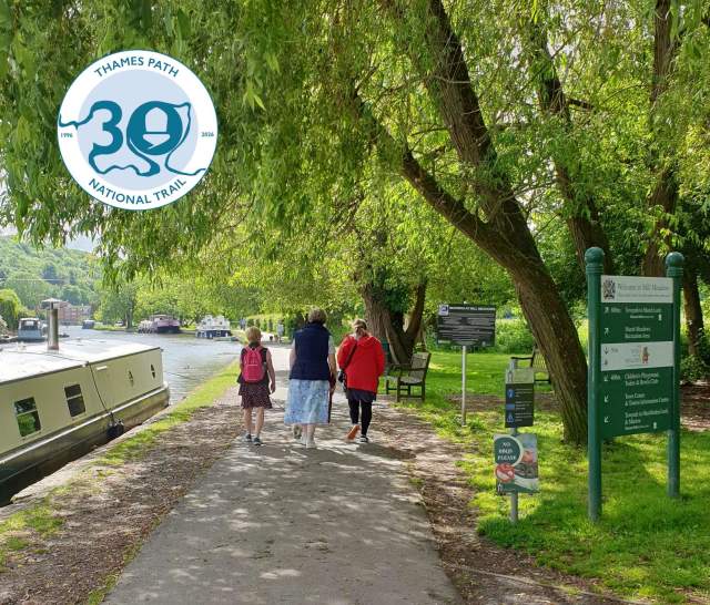 People walking along the Thames Path in Henley with boat moored