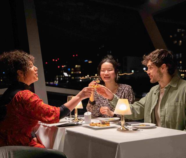 3 people enjoying drinks onboard City Cruises at night
