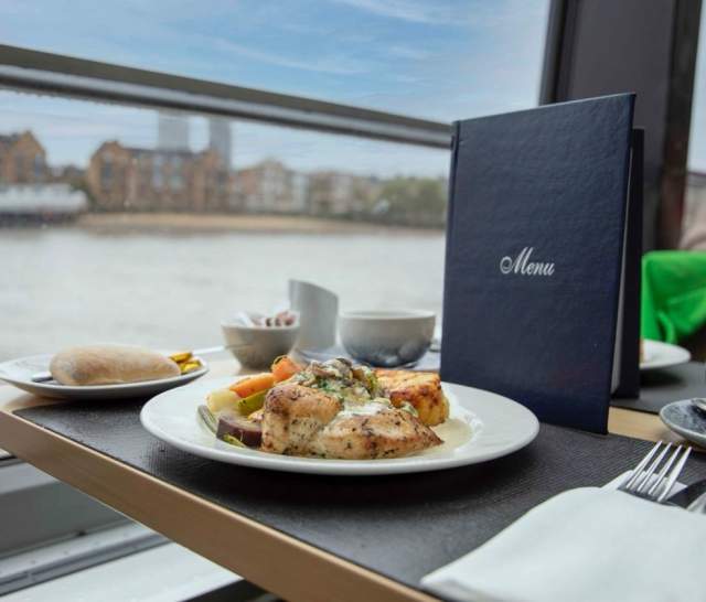 Food on a plate in front of window on the river.