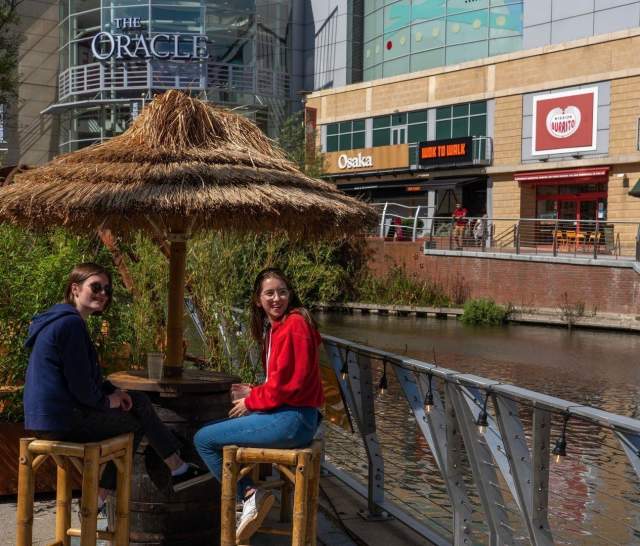 two people sat at a table beside the river kennet.