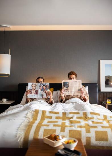 Couple reading newspapers in hotel bed