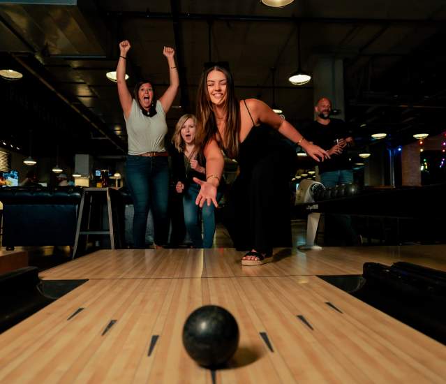 A group of friends celebrating on a duckpin bowling lane at PINS Mechanical