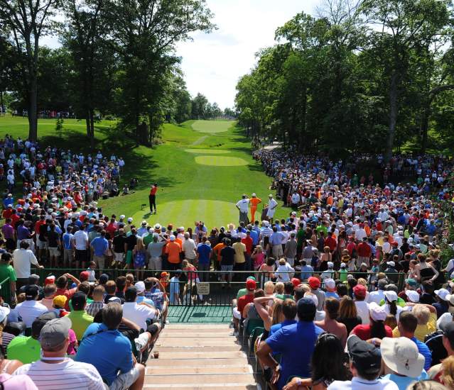 Golfer teeing off from the 15th tee at the Memorial Touranment while fans surround the tee box.