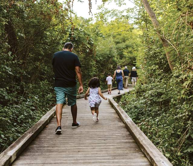 A family running down the boardwalk at Kiwanis Riverway Park