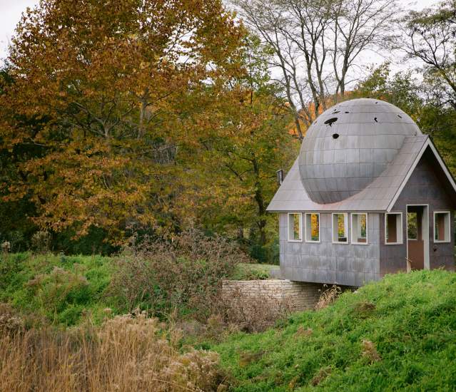 Watch House public art installation surrounded by trees and grass in fall color.