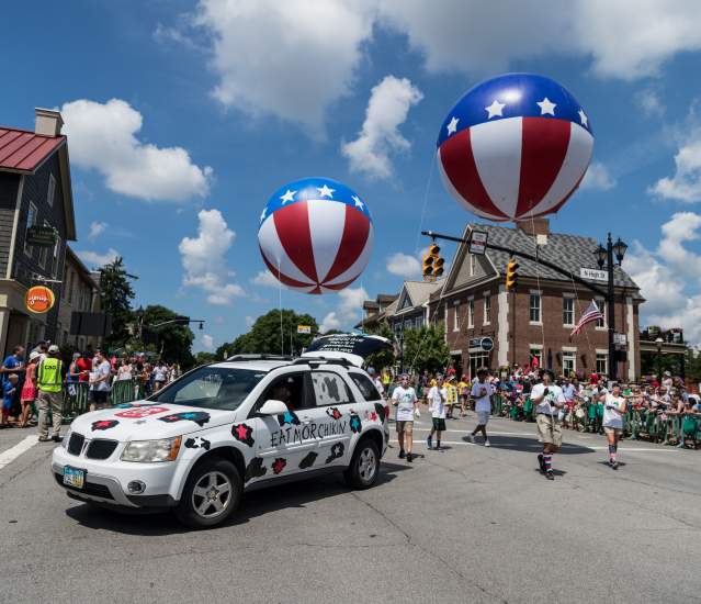 Red white and blue balloons floating behind a car and parade float in Historic Dublin.
