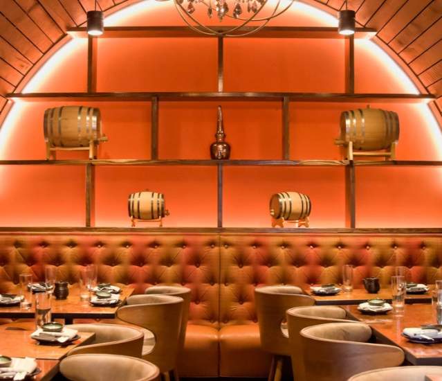 Song Lan's private dining room featuring a cozy, dimly lit booth with orange walls, wooden accents, and upholstered seating.