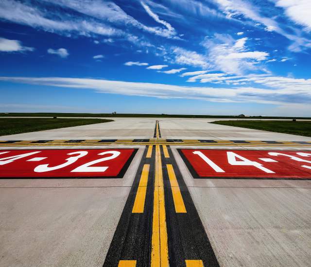 Low angle photo of an empty Runway 14-32 at Rapid City Regional Airport under a partly cloudy sky.